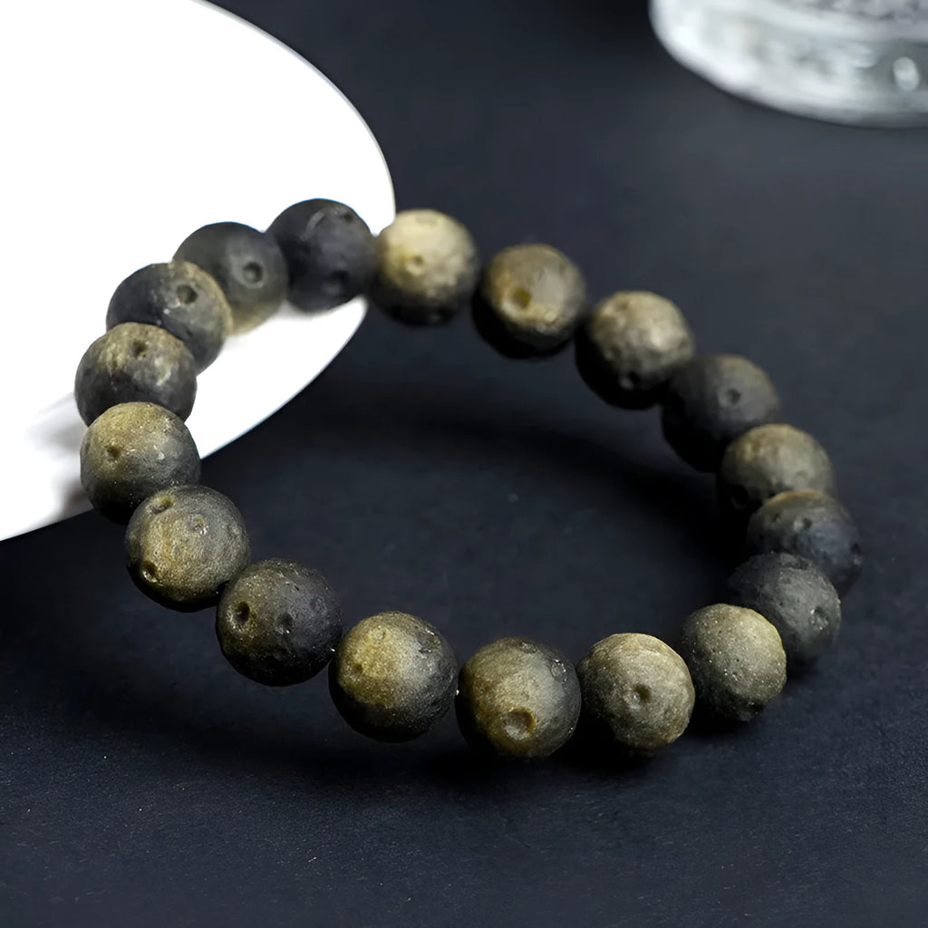 Natural obsidian crater ball bracelet in silver stone or gold finish, showing textured bead detail.