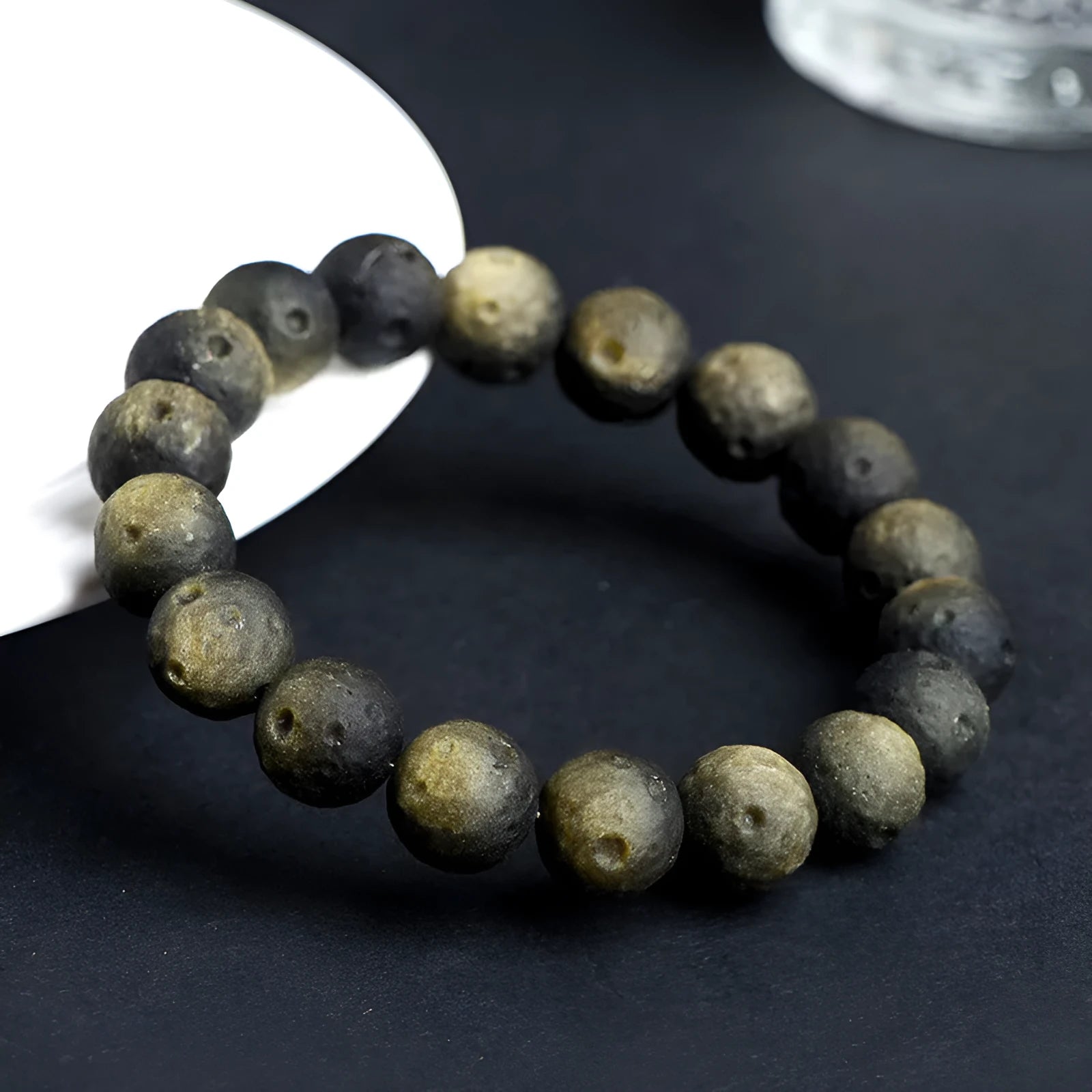 Natural obsidian crater ball bracelet in silver stone or gold finish, showing textured bead detail.
