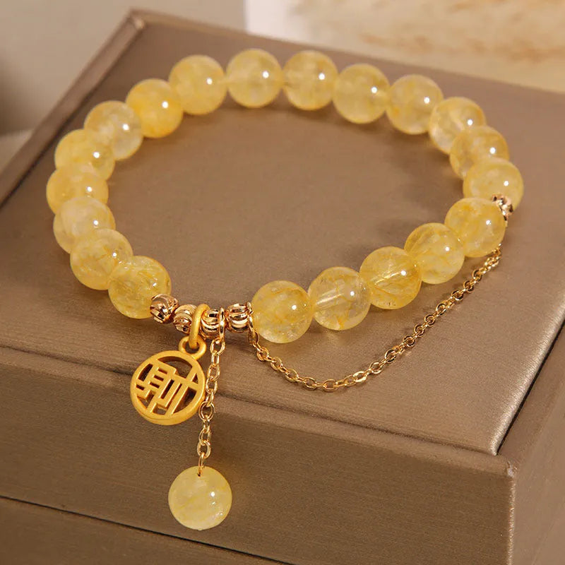 Close-up of a women's natural citrine bracelet with an electroplated Chinese character tassel.