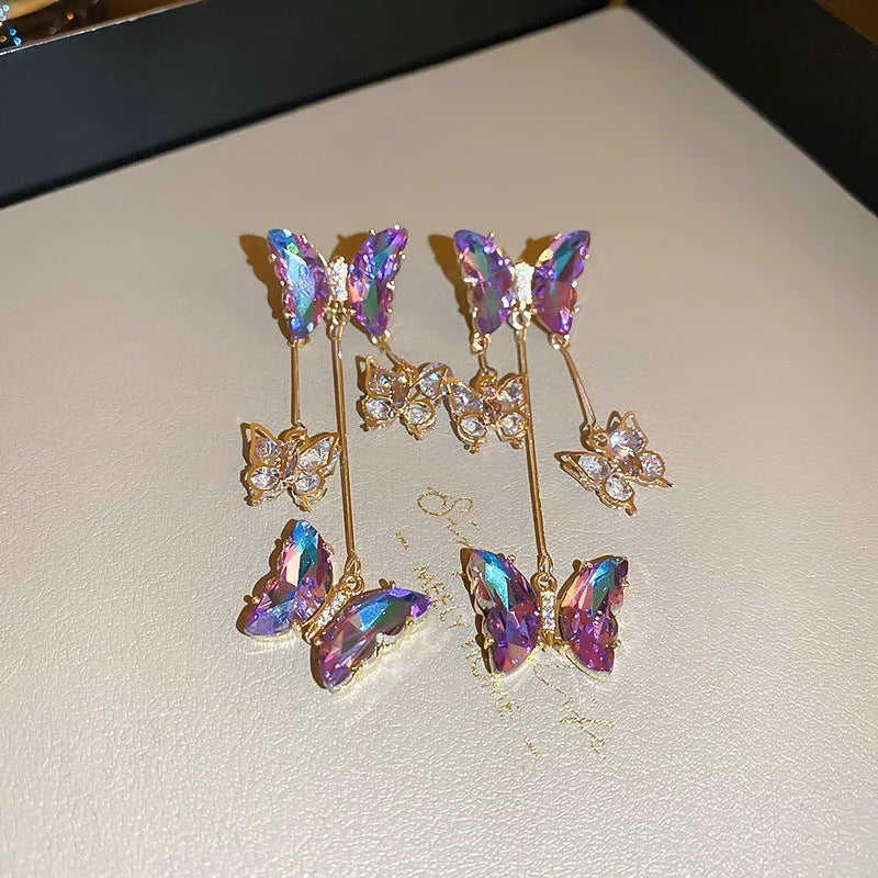 Silver needle alloy drop earrings featuring a blue purple butterfly design with crystal accents and tassel details.