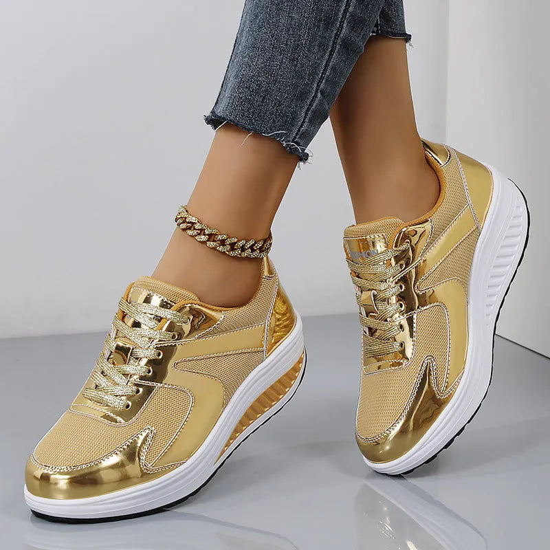 Gold women's mesh platform trainers with cross strap and thick sole on a white background.