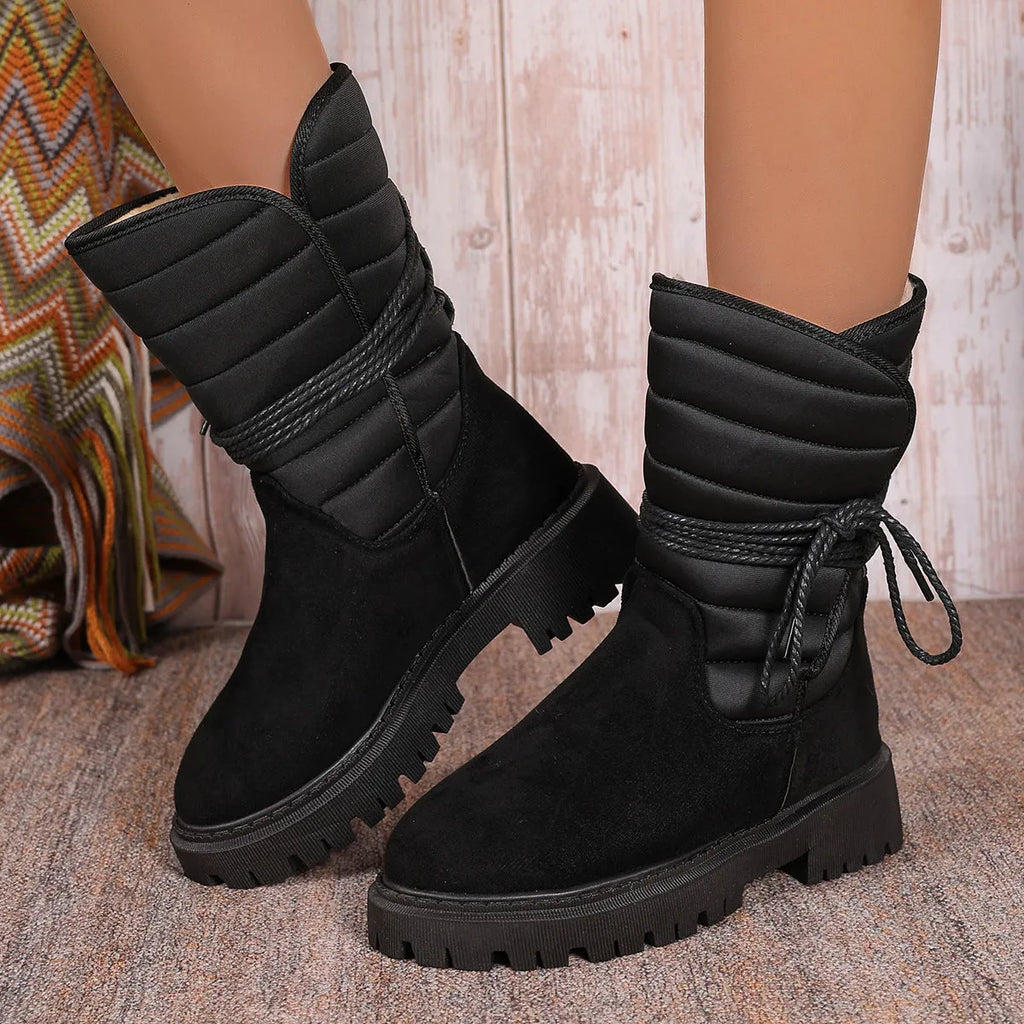 Women's black chunky heel snow boots with suede upper and lace-up design on a white background.