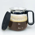 Transparent borosilicate glass coffee maker with black silicone cover and handle on a stovetop.