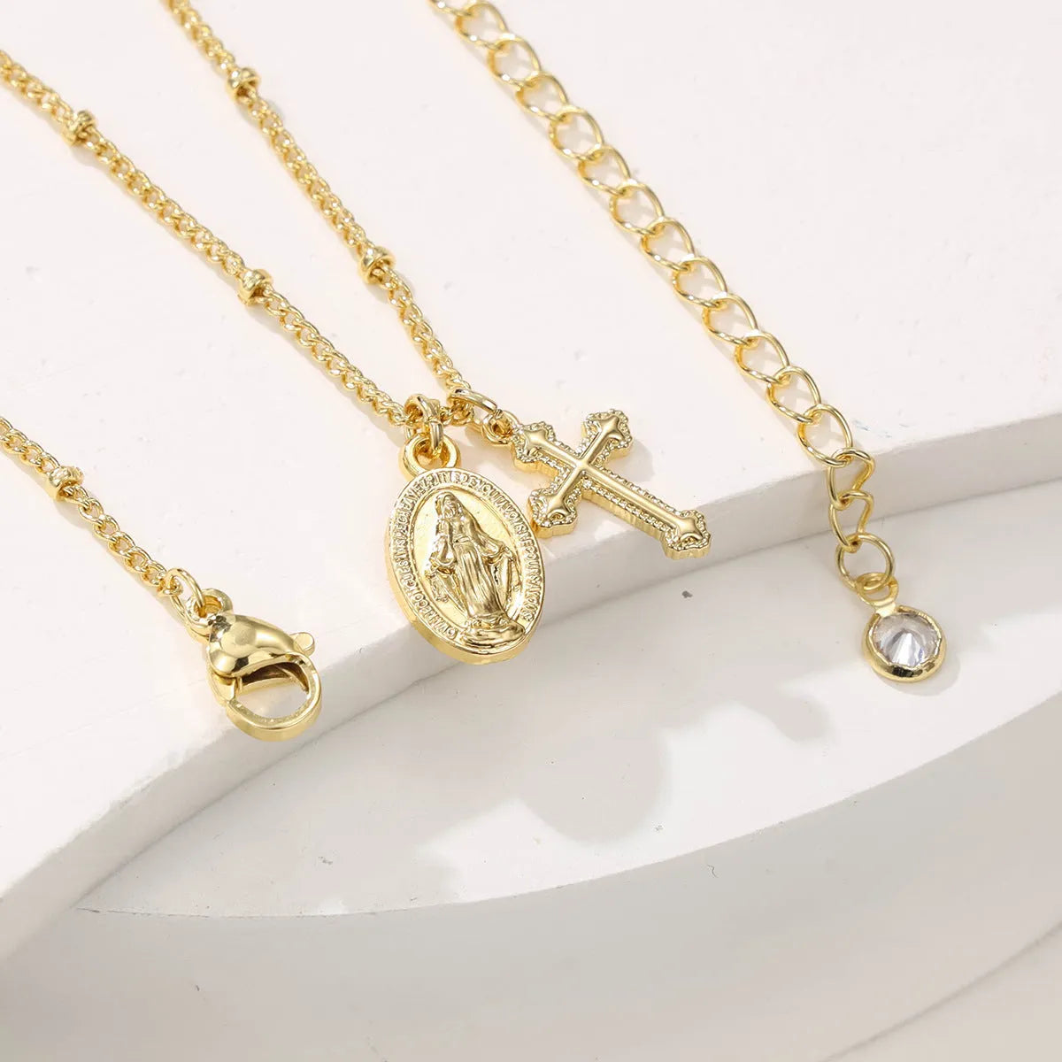 Geometric Virgin Mary and cross pendant necklace in 18K gold colour on a copper chain.