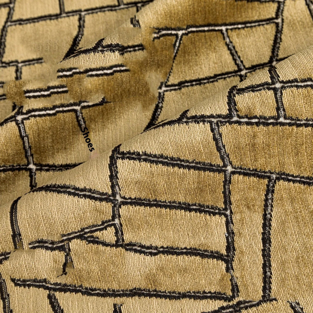 Gold geometric abstract patterned square cushion on a grey sofa.