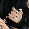 Handmade black and pink heart design artificial nails with bow, Xingx pattern, and cat's eye finish.