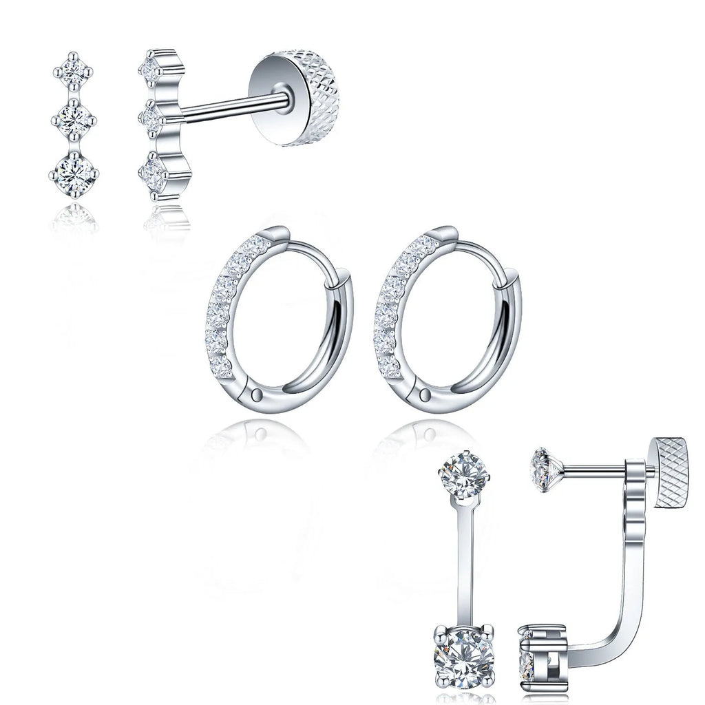 Three pairs of titanium steel ring-shaped geometric stud earrings with zircon inlay on a grey surface in steel and gold tones.