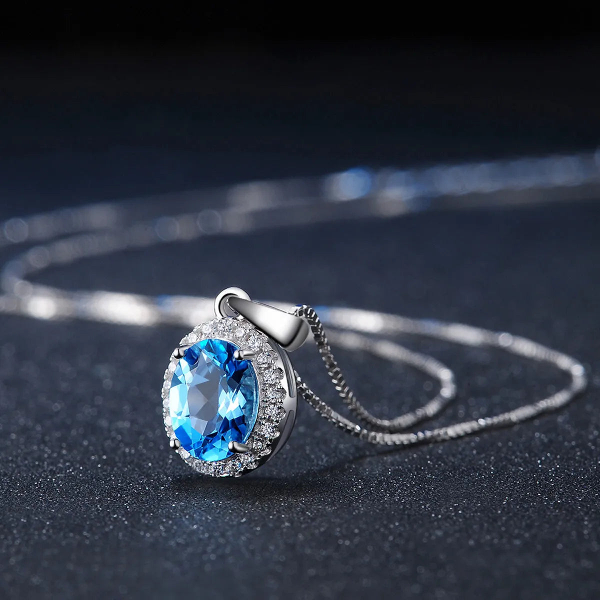 Women's sterling silver jewellery set with blue topaz stones, showing geometric earrings, necklace, ring, and pendant.