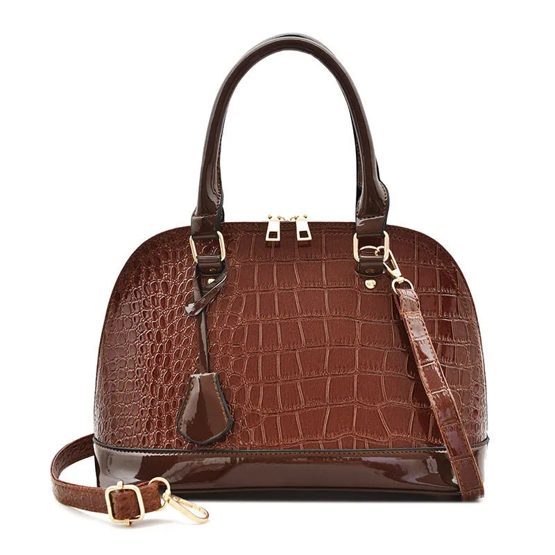 Shiny black PU leather crossbody bag with a structured shell shape, shown with a shoulder strap.