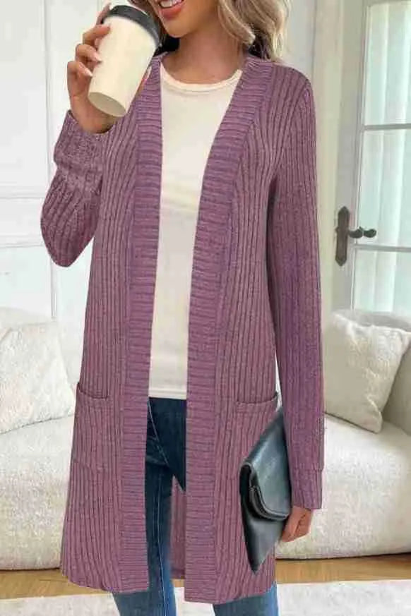 Woman wearing a loose grey long sleeve knitted cardigan jacket with pockets.