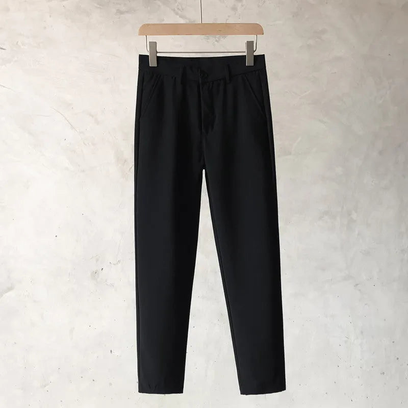 Boy wearing slim straight wool trousers in a neutral colour, showing tapered leg and straight hem.