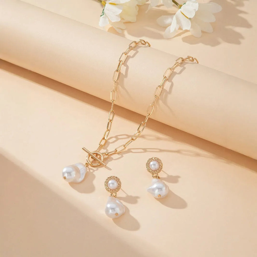 Gold-colour iron necklace and earring set with a baroque pearl pendant on a woman.