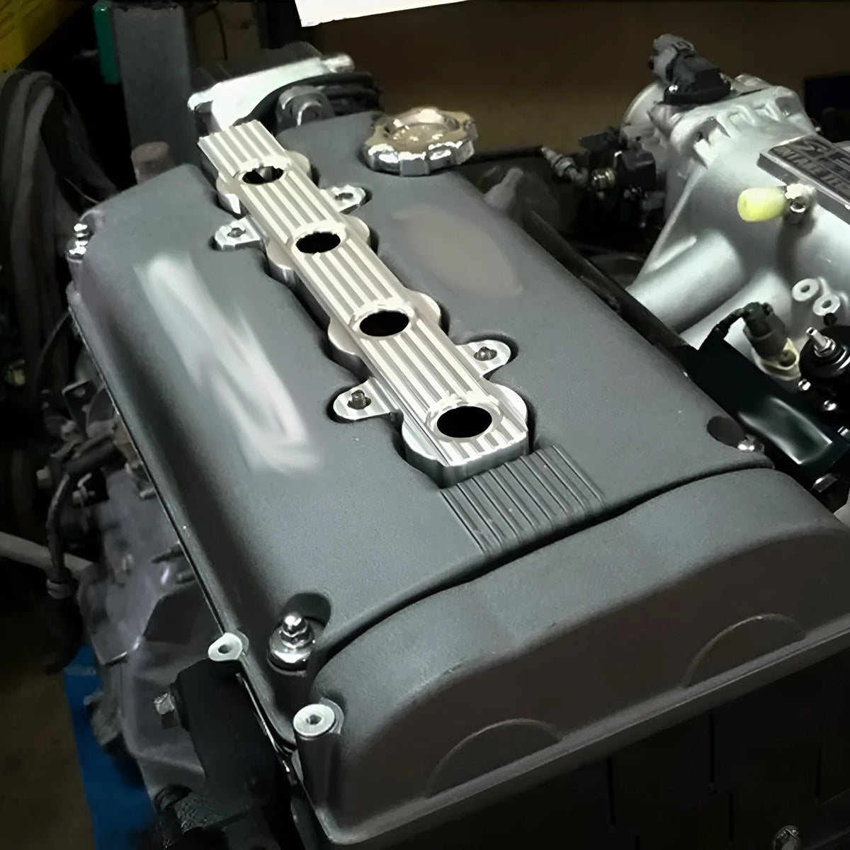 Aluminium alloy engine wiring harness housing cover in blue, red, and silver finishes.