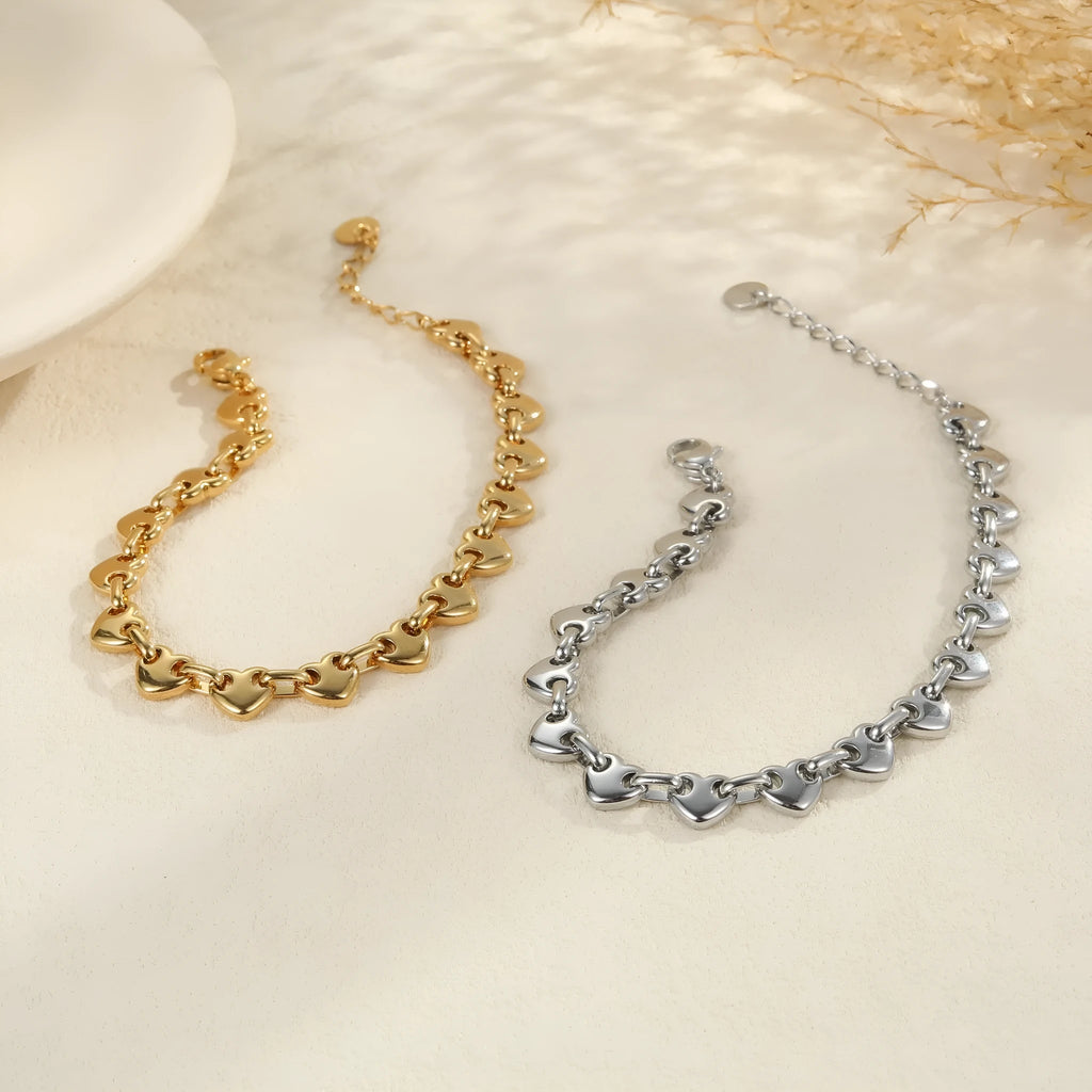 Women's stainless steel bracelet featuring a hollowed-out geometric heart design in gold or steel finish.