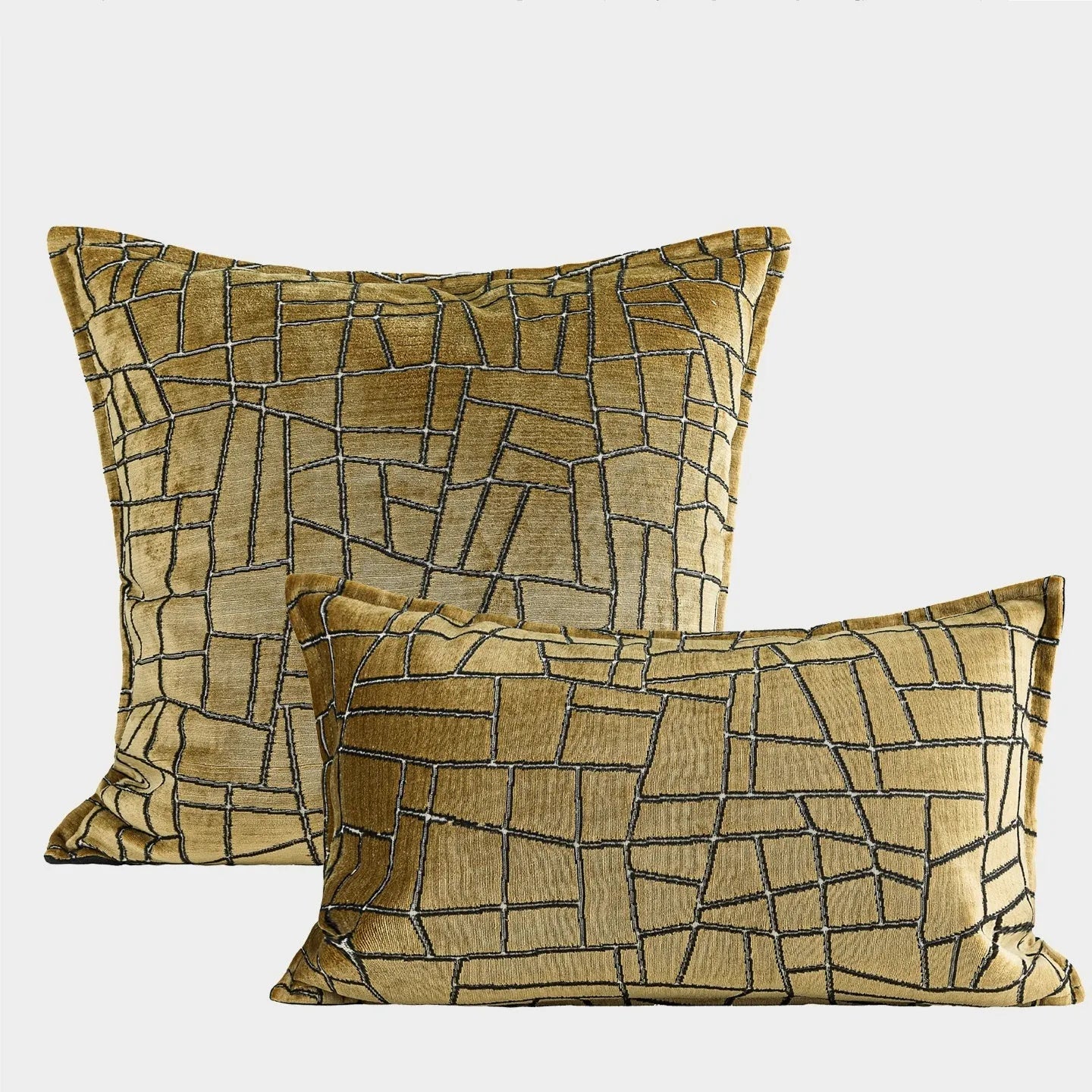 Gold geometric abstract patterned square cushion on a grey sofa.