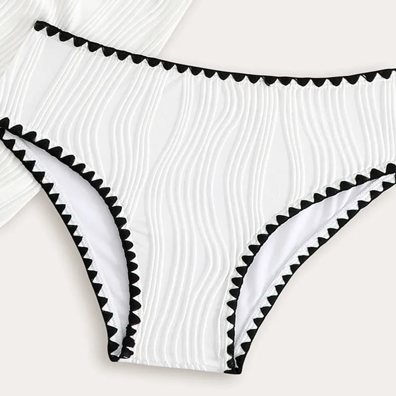 Solid white three-piece girls swimsuit set with top, pants, and skirt on a beach setting.