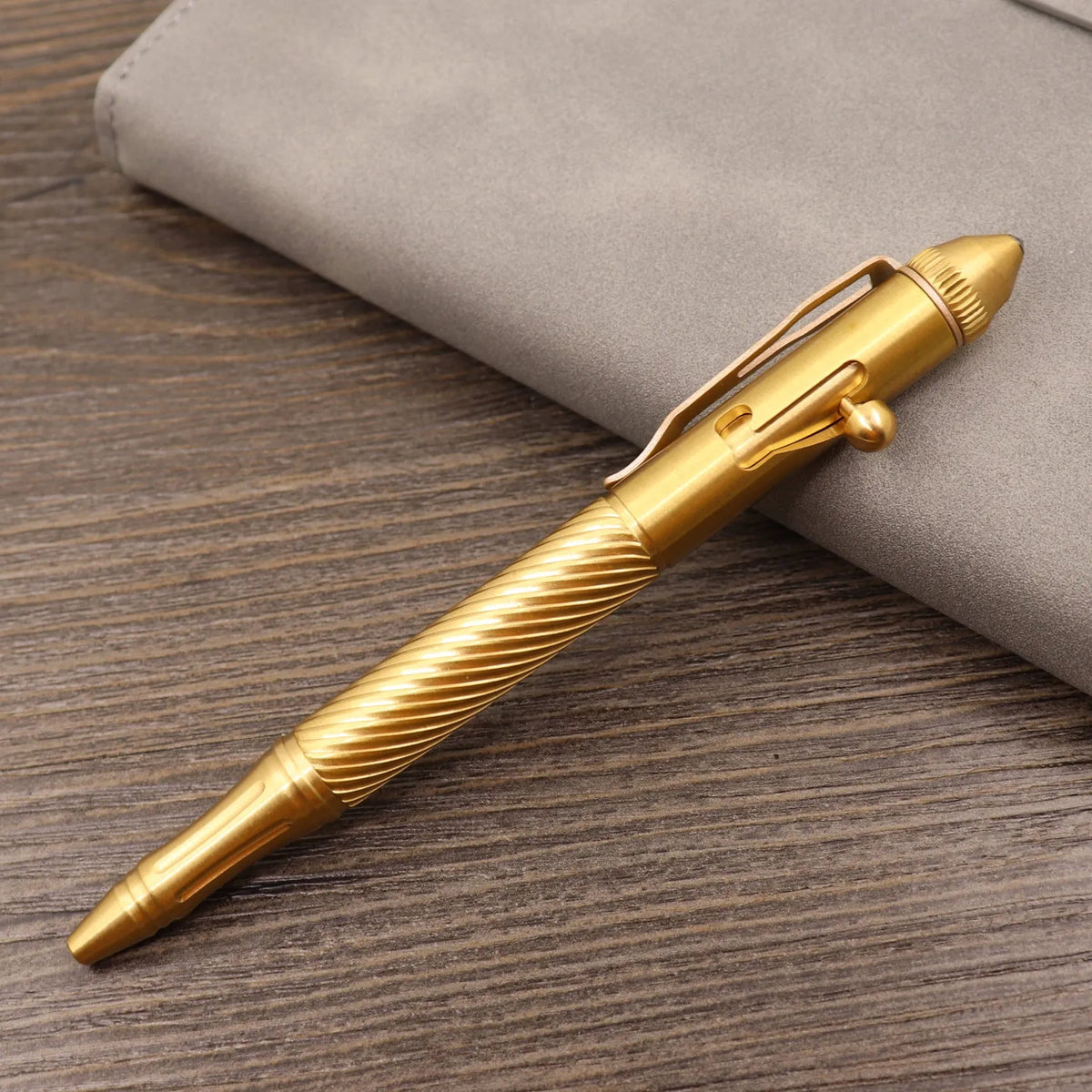 Brass tactical pen with bolt-action mechanism and cylindrical barrel showing six-ring grip detail
