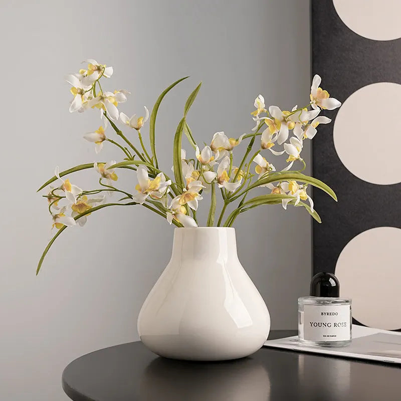 Black ceramic vase with round belly shape and two white flower ornaments arranged decoratively