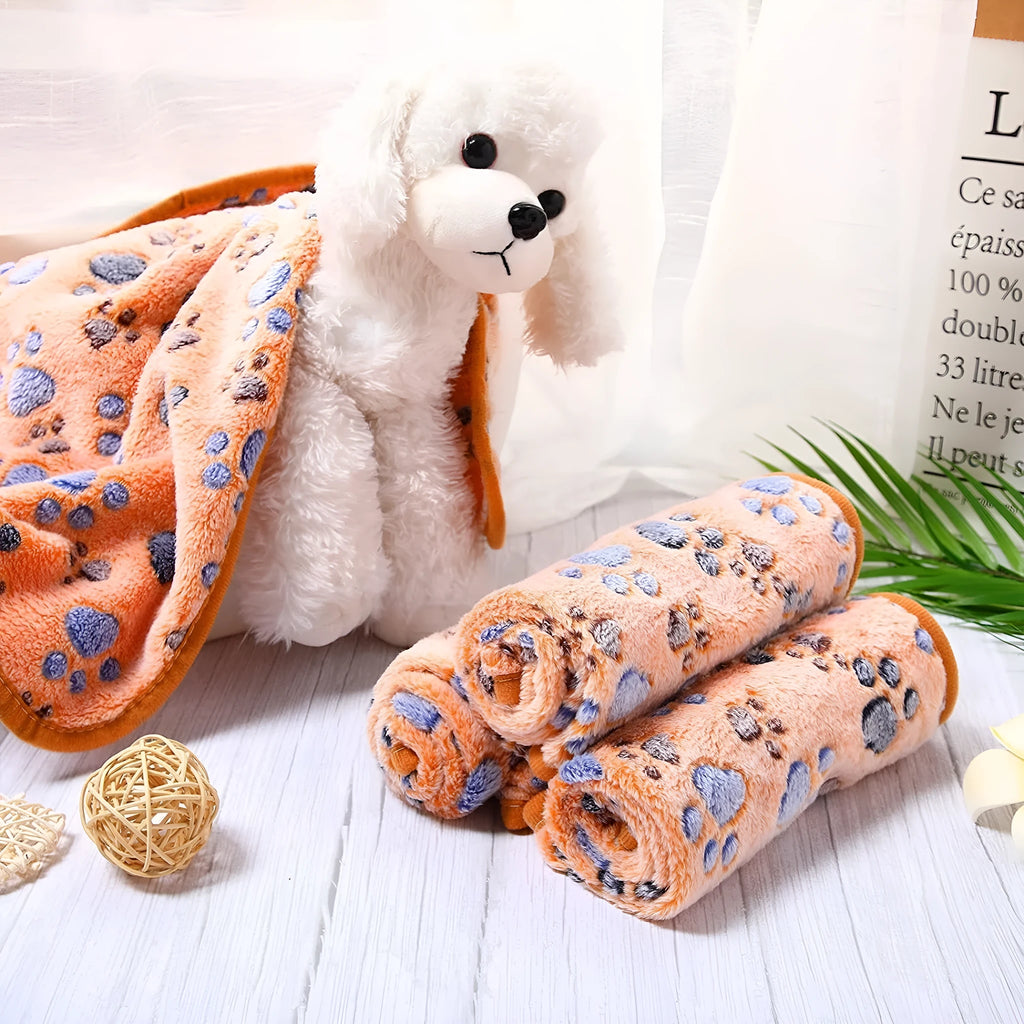 Coral fleece pet blanket with dog paw print pattern in beige, shown alongside size options from small to extra large.