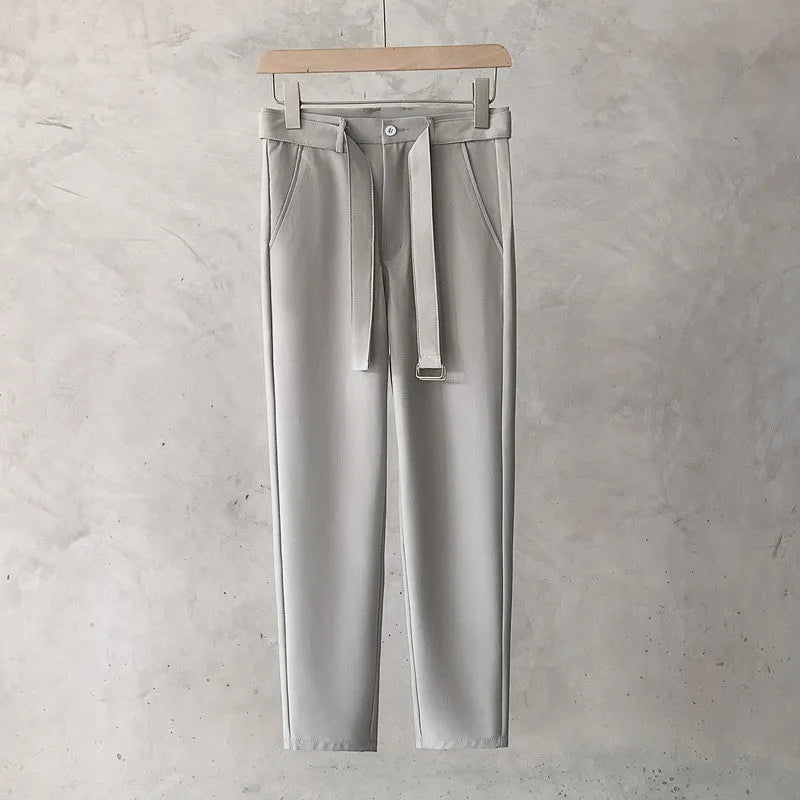 Boy wearing slim straight wool trousers in a neutral colour, showing tapered leg and straight hem.