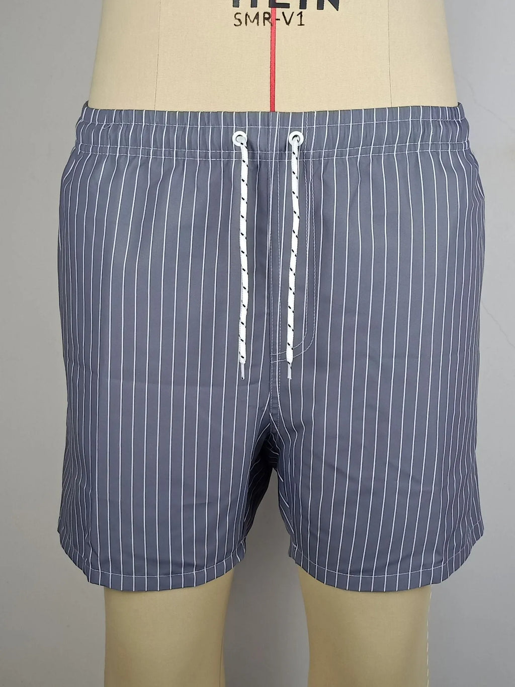 Striped polyester beach shorts in navy blue, shown with straight leg openings and triangle lining.