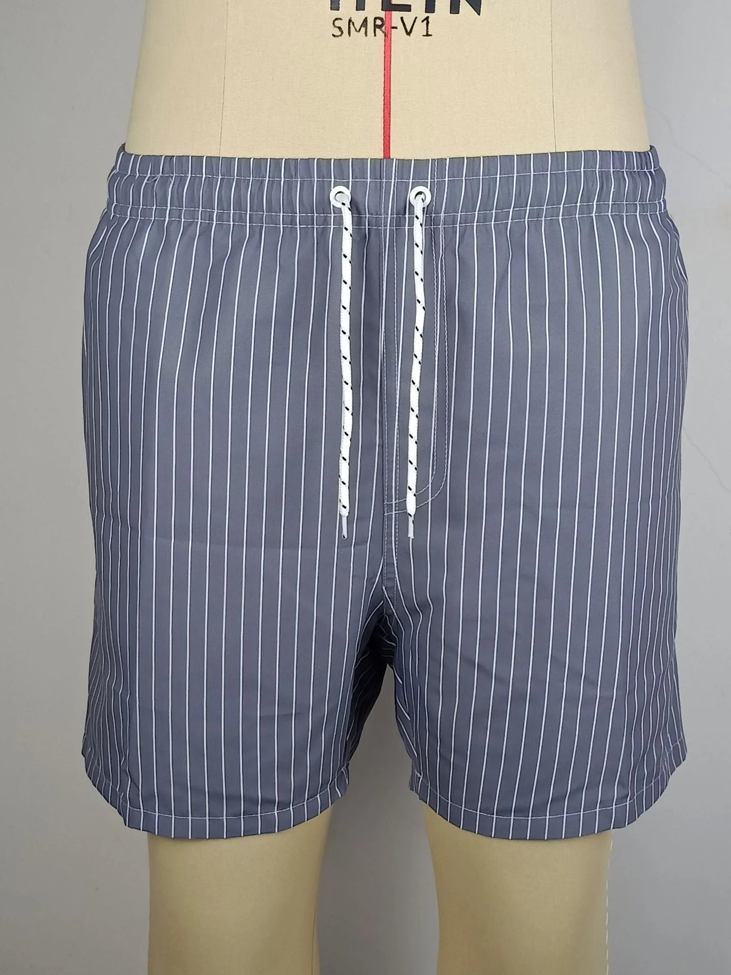 Striped polyester beach shorts in navy blue, shown with straight leg openings and triangle lining.