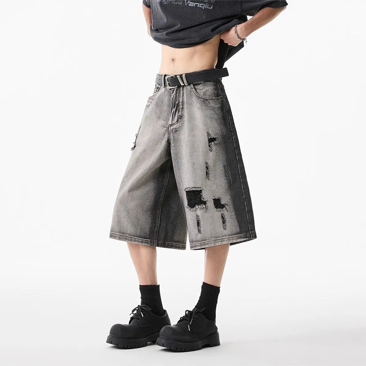 Grey distressed denim shorts with a loose cropped fit and hole details on a mannequin.