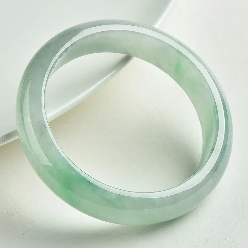 Natural light green jade bracelet with a metal clasp, shown on a wrist.