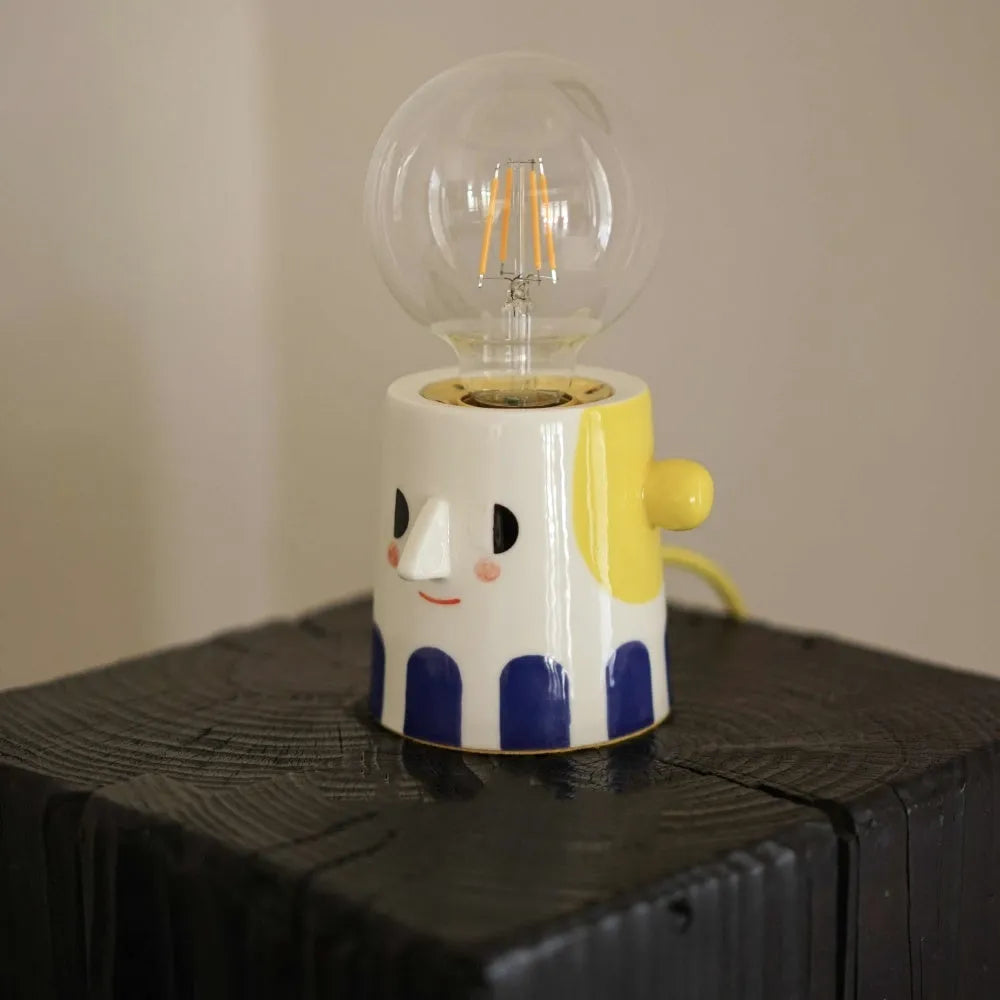 Handmade ceramic bedside lamp with ball headlight design on wooden nightstand