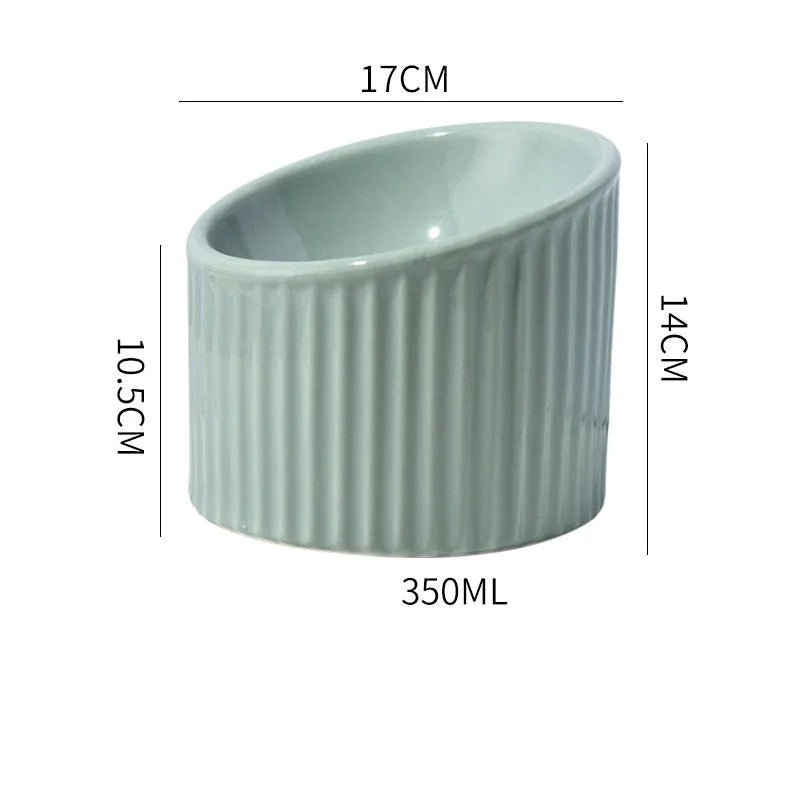 A dark green elevated ceramic cat bowl with a tilted, round design on a wooden surface.