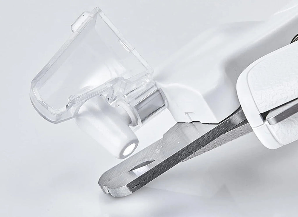 White pet nail clippers with LED light, transparent guard, and a nail file on a table