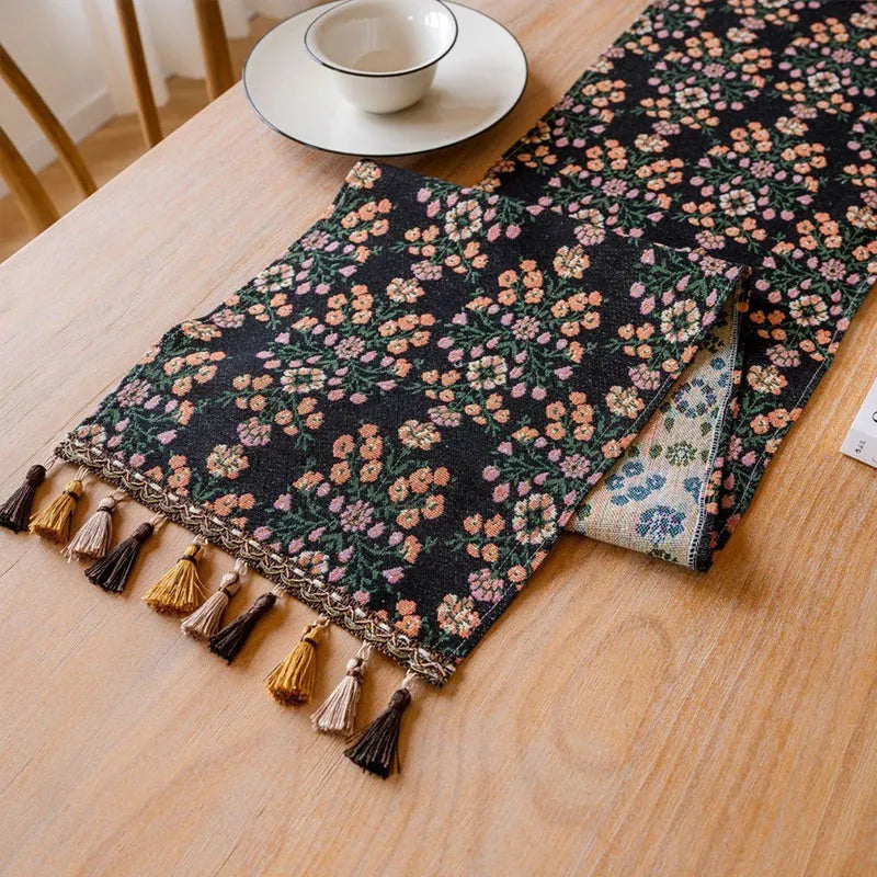 Dark blue Nordic jacquard table flag with striped bouquet pattern and tassel fringe on a wooden table.