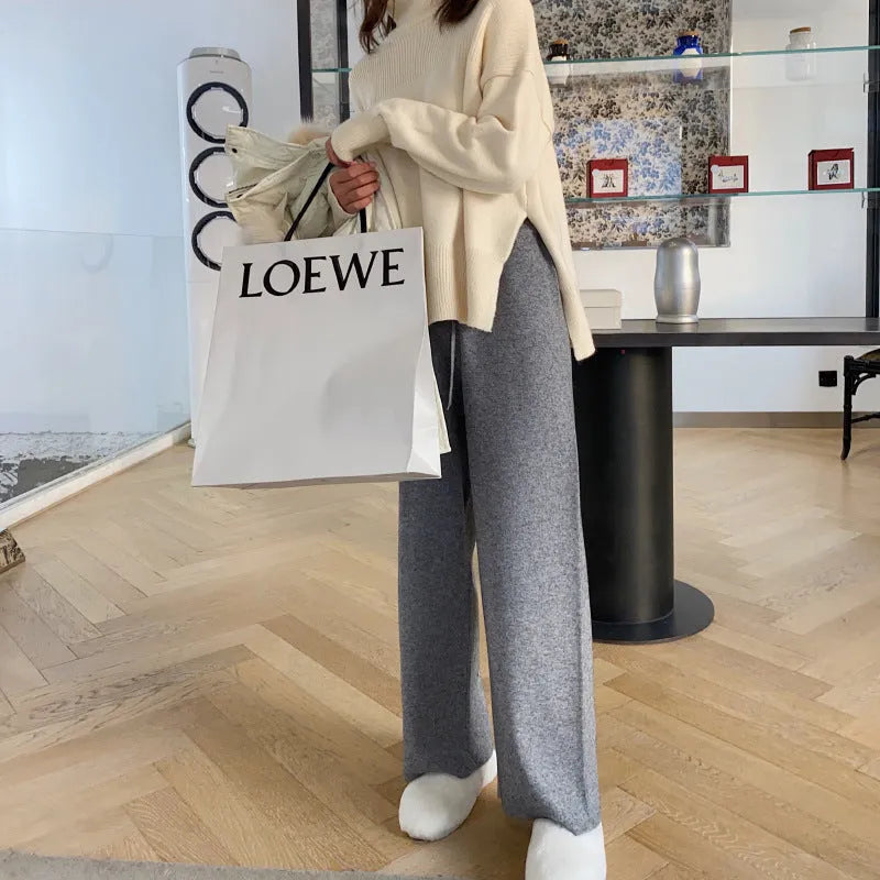 Women's high-waist knitted wide-leg trousers in cream white, showing straight-leg cut and drooping hem.