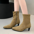 Brown square toe ankle boots with a side zipper and pointed stiletto heel on a wooden floor.