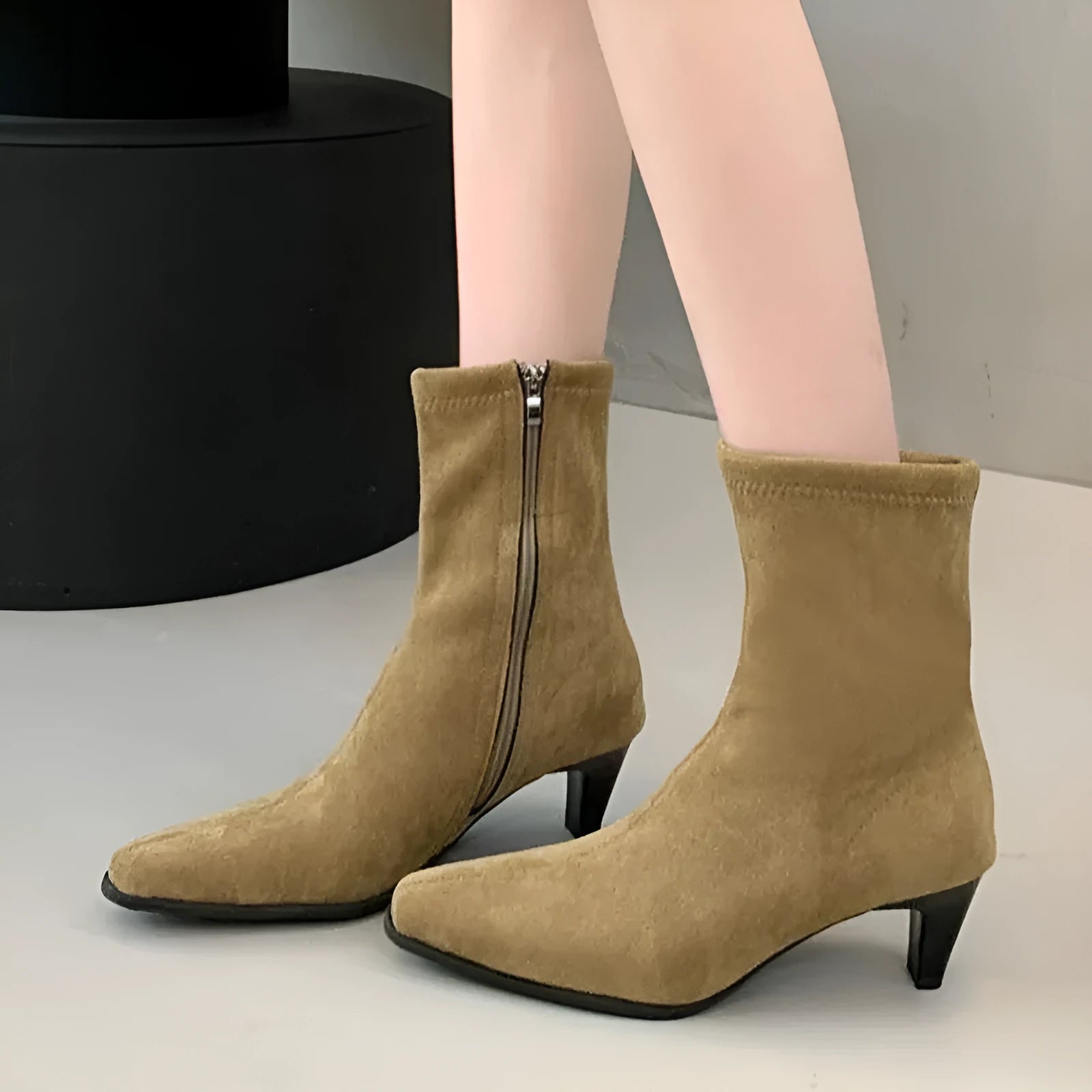 Brown square toe ankle boots with a side zipper and pointed stiletto heel on a wooden floor.