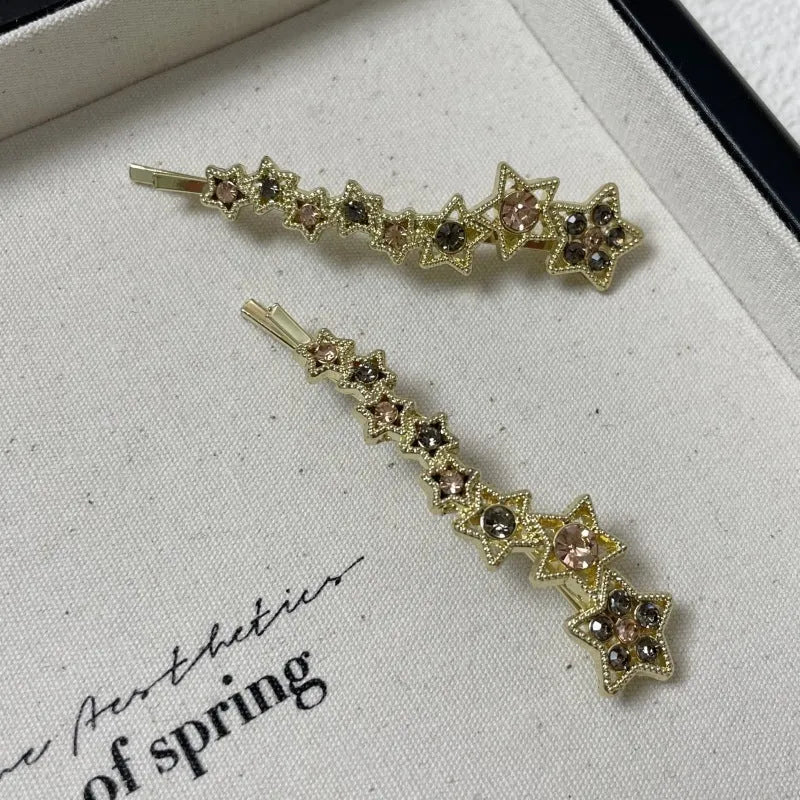 Gold electroplated rhinestone barrettes with side clip design featuring star and letter charms