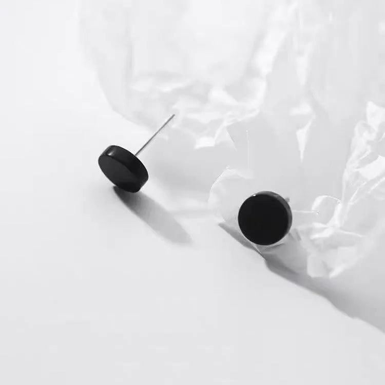 A pair of flat, round S999 sterling silver ear studs on a plain background, shown in silver and black colour options.