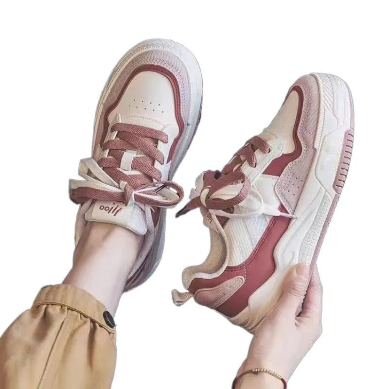 Pink and white low-top sneaker with a height-increasing rubber sole.