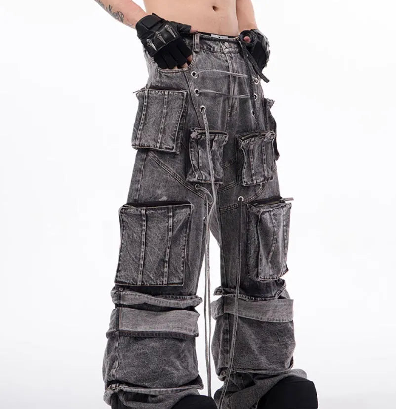 A pair of grey distressed denim overalls with rope stitching, shown on a model.
