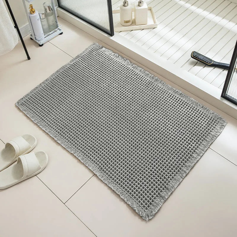 Checkered patterned non-slip absorbent bathroom floor mat in a neutral colour on tiles.