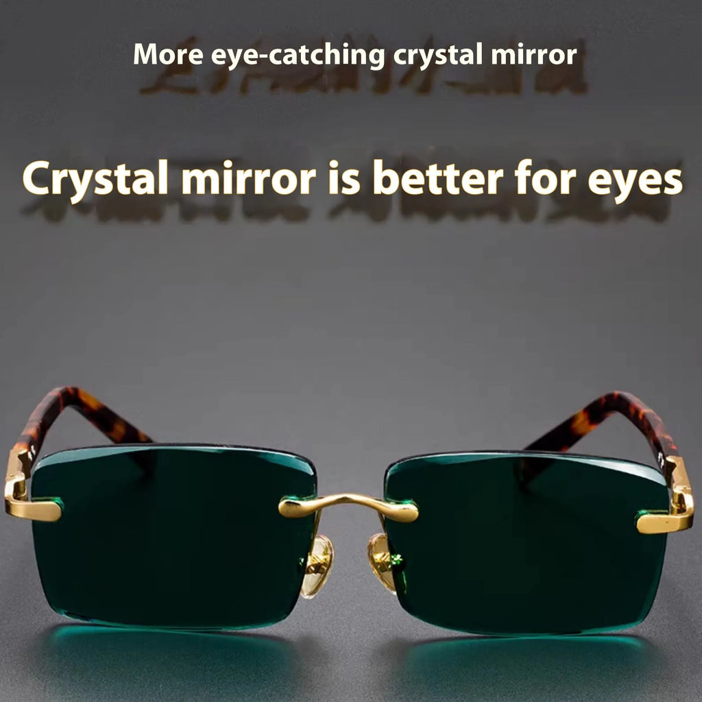 Dark green frameless crystal sunglasses with a matching case and cleaning cloth on a table.