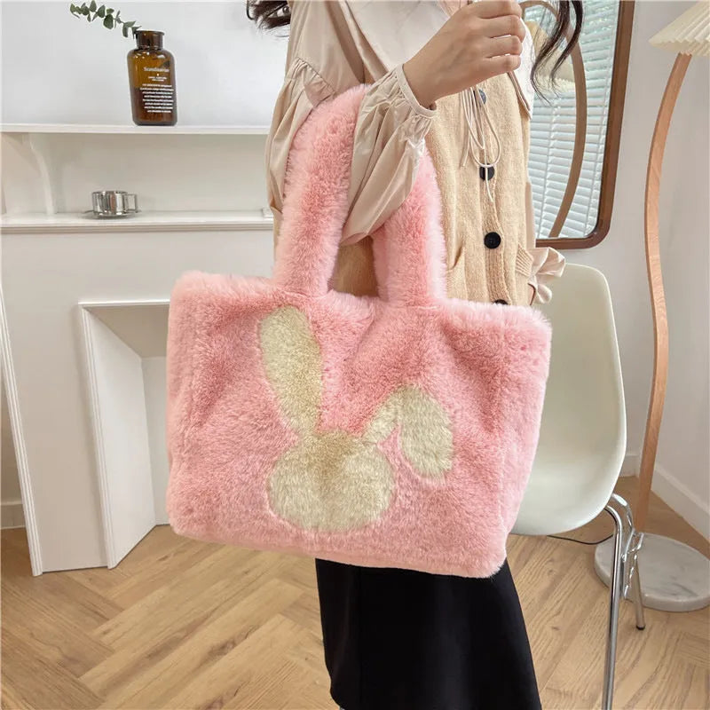 Plush shoulder bag with cartoon rabbit ears design in a solid colour.