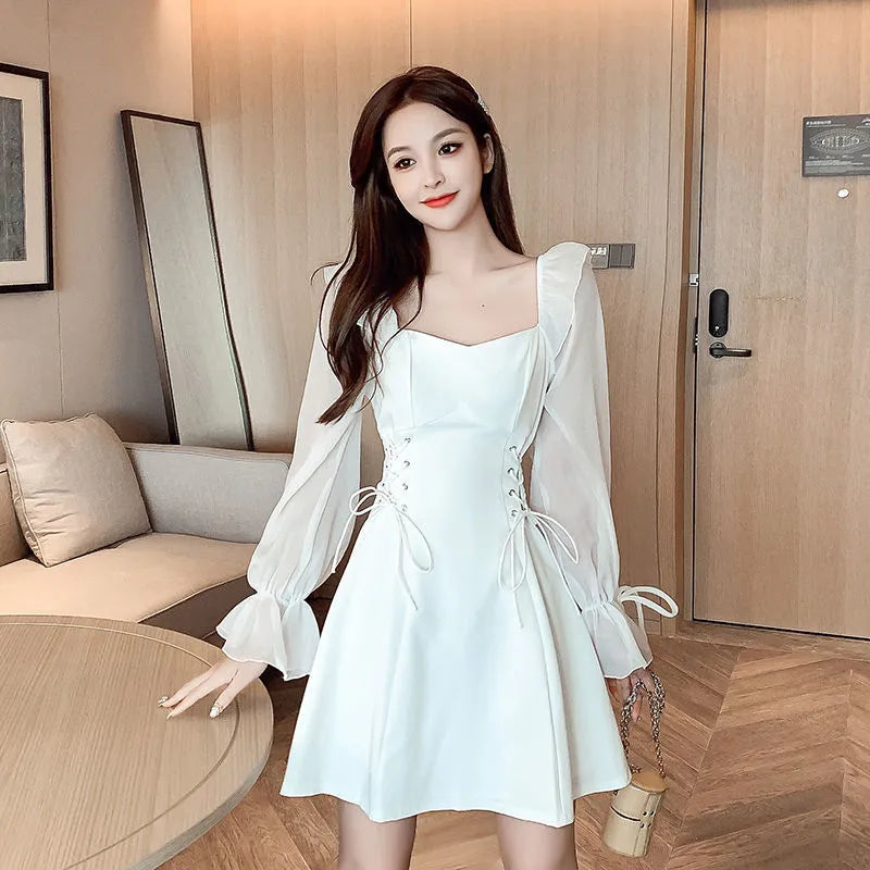 White chiffon patchwork dress with long sleeves and a waist-slimming silhouette on a hanger.