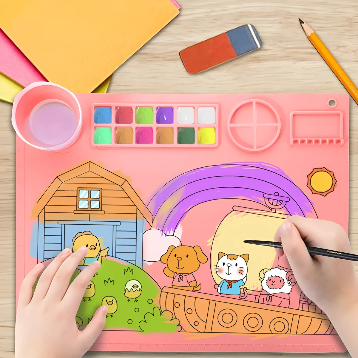 Light blue silicone painting mat with two round mixing bowls, placed on a wooden table with paintbrushes.