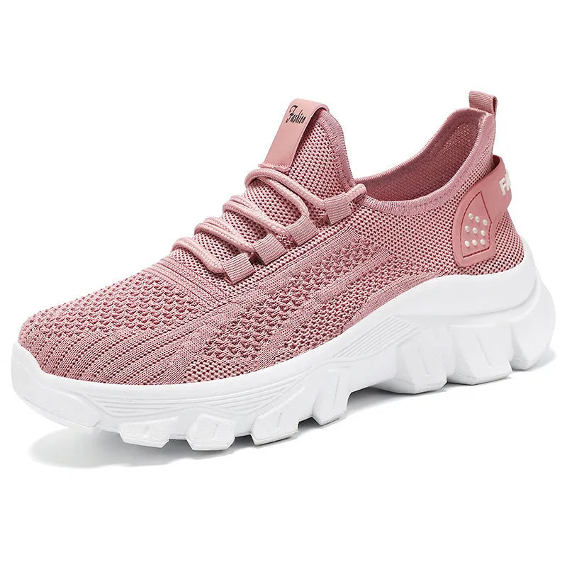 Women's white Flyknit lace-up sneakers with a thick PVC sole and round toe on a neutral background.