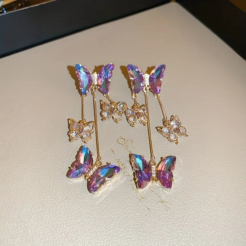Silver needle alloy drop earrings featuring a blue purple butterfly design with crystal accents and tassel details.