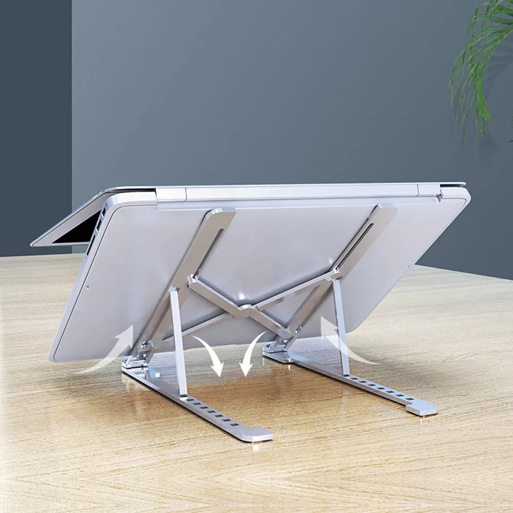 A folded deep grey aluminium laptop stand next to an open silver laptop on a desk.