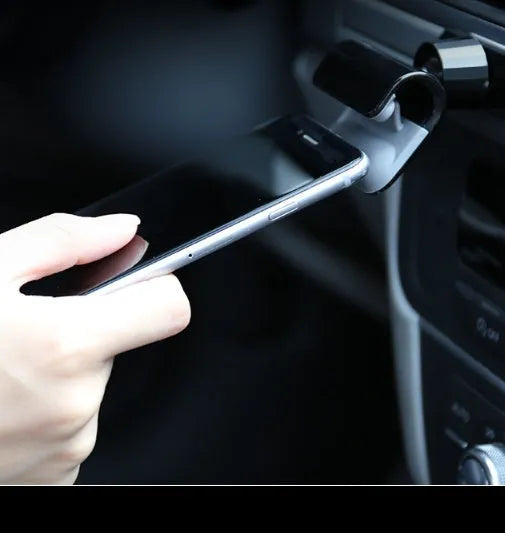 Black universal gravity car phone holder mounted on a dashboard, showing 360-degree rotation.