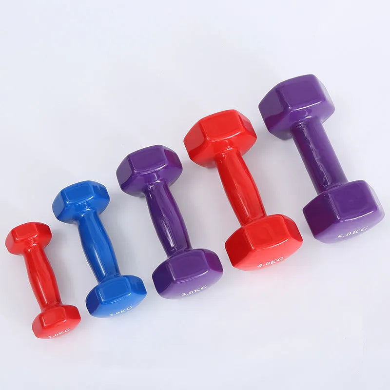 Bright green and pink plastic fitness dumbbells with glossy finish on a wooden floor.