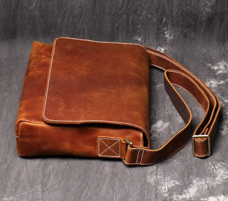 Vintage brown men's leather messenger bag showing interior compartments and adjustable shoulder strap